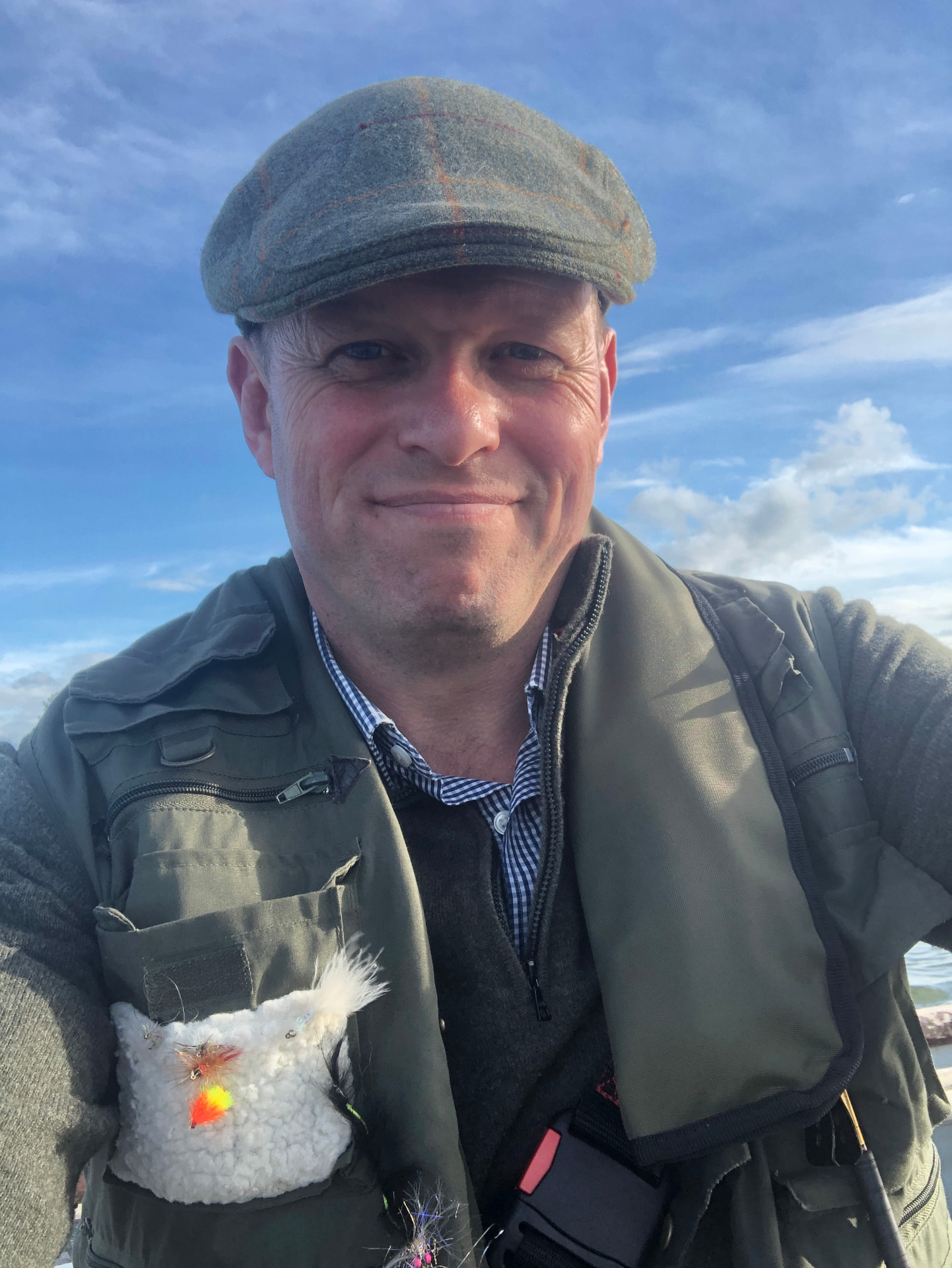 James Alexander, founder of UnHooked, wearing a tweed cap and fishing vest with tied flies